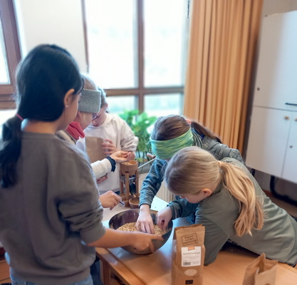 Kinder der Grundschule Taching beim Flocken quetschen